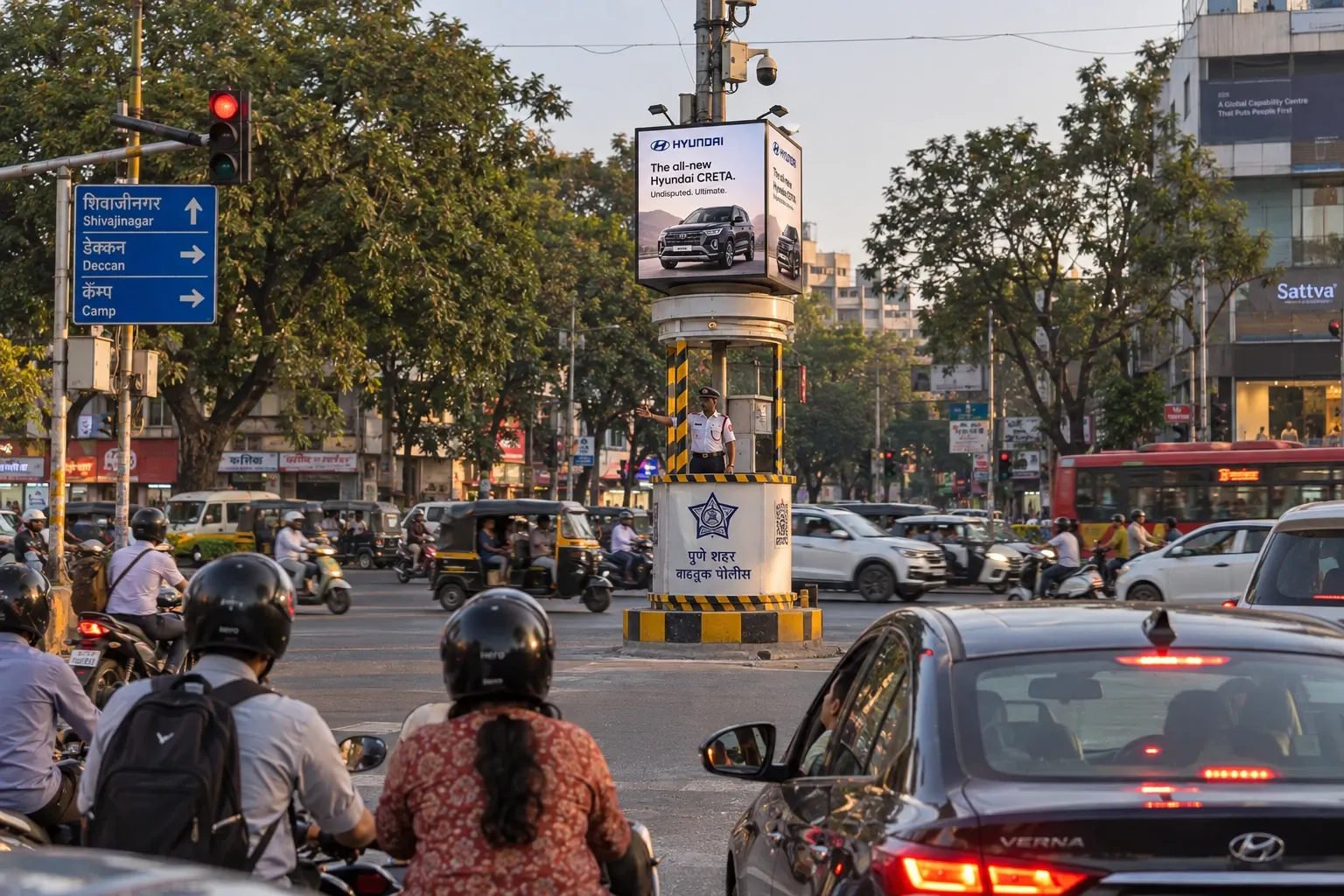 A lit billboard on top of a traffic tower at a busy city junction